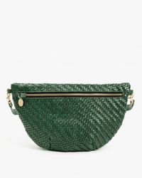 The Clare V. Woven Zig-Zag Grande Fanny in Evergreen features green woven leather, a gold zipper and hardware, an adjustable strap, and a small round gold charm on one side.