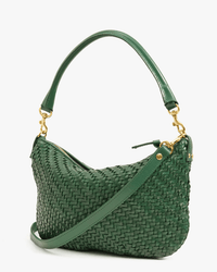The Clare V. OLD-Woven Zig-Zag Petit Moyen Messenger in Evergreen is a green woven leather bag with gold hardware, a curved top handle, and an adjustable shoulder strap, shown against a white background.