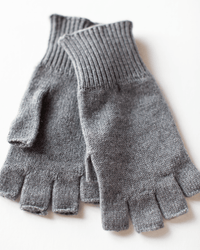 A pair of COLORI Fingerless Gloves in Kensington, gray cashmere with ribbed cuffs, made in Italy, are shown lying flat and overlapping on a white surface.