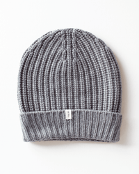 The COLORI Ribbed Beanie in Kensington is a cozy gray hat with a folded brim and small white tag, shown flat on a white background—perfect for winter style.