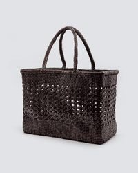 The Dragon Diffusion Cannage Max in Dark Brown is a rectangular bag with two braided handles and an openwork middle section, shown against a light gray background.