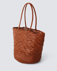 The Corso Bucket Bag in Tan by Dragon Diffusion features two braided handles, a textured woven pattern, and a rounded base, shown against a plain light gray background.
