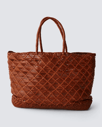 The Dragon Diffusion EW Corso Bag in Tan is a large bag featuring two handles and a diamond-patterned woven leather design, displayed against a plain light grey background.