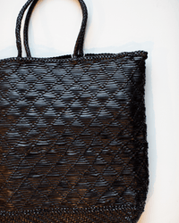 A close-up of the Dragon Diffusion NS Corso Bag in Black shows its diamond-patterned woven leather and dual handles against a white background, perfectly reflecting this tote's refined style.