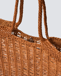 Close-up of the Dragon Diffusion Window Basket in Tan, showing its hand-woven design, braided handles, and a small metallic snap closure near the top edge.
