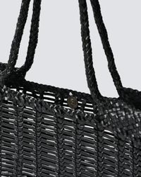 Close-up of the Dragon Diffusion Window Shopper in Black, a hand-crafted bag featuring braided handles and a metallic snap button closure, shown against a plain light gray background.