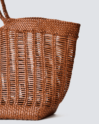 A close-up of the Dragon Diffusion Window Shopper in Tan, showing its vertical and diagonal woven pattern, sturdy rim, and partially visible braided handle against a plain light gray background.