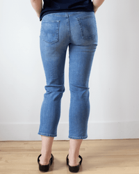 A person wearing Edwin Bree in Dreamland jeans and black shoes stands on a wooden floor facing away from the camera, hands partially visible by their sides.