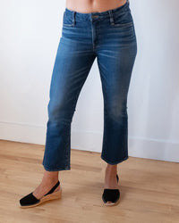 A person wears Edwin Lark Slate Ankle Bootcut jeans in Terrace and black wedge sandals, standing on a light wood floor against a white wall. The photo is cropped above the waist, so their face and upper body are not visible.