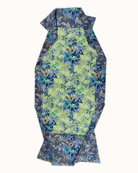 The Fleur 2 Scarf in Kiwi by Épice features a blue and green floral pattern on fabric cut into an elongated, irregular octagon, displayed on a light background—ideal for winter wear or styling as an Épice accessory.