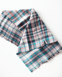 The Épice Small Square Check Scarf in Turquoise is a soft, fringed wool accessory with a colorful check pattern, shown laid flat on a white background.