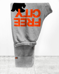 FREE CITY Large 3/4 Sweats in Heather Electric, made in LA, folded with "FREE CITY" in bold orange letters and a black dove above the text. These drawstring sweatpants are hand screen printed and shown against a plain background.