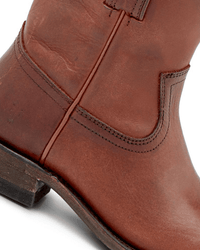 Close-up of the FRYE Billy Short in Cognac, highlighting brown leather, detailed stitching, a low stacked heel, and the slightly worn texture that defines classic Western boots.