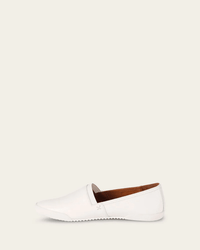The FRYE Melanie Slip On in White is a vintage leather sneaker with a pointed toe and flat rubber sole, displayed from the side against a plain beige background.