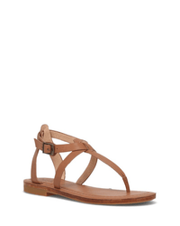 The FRYE Taylor Sandal in Tan features thin crisscross straps, an adjustable buckle ankle strap, and a thong toe design, all crafted from full grain leather and shown on a white background.