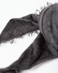 Close-up of the Grisal Love Cashmere Scarf in Black Coffee, featuring a soft, slightly worn texture with frayed edges and visible threads on a white background.