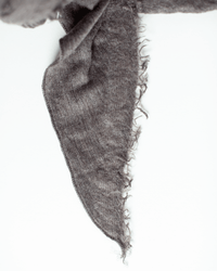 A close-up of the Grisal Love Cashmere Scarf in Brown Top, featuring a soft, triangular design with frayed edges, laid on a white background.