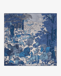An intricate blue illustration of wild animals and a sunlit forest captures the vibrant detail found on the Inoui Editions Square / Carre 100 Reve in Blue scarf.