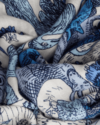A close-up of Inoui Editions' Square / Carre 100 Reve in Blue shows textured fabric with detailed blue and navy animal illustrations on a white background, suggesting the luxurious feel of this wool, silk, and cashmere scarf.