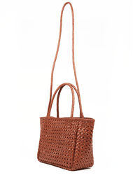 The Annette Petit Cuir Bag in Picante by Maison N.H Paris is a brown woven mini tote with two short handles and a long braided shoulder strap, handmade in India and shown against a white background.
