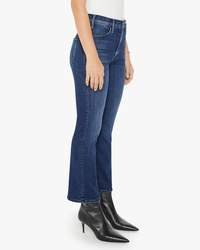 Wearing a white top, Mother Lil Hustler Ankle in Heirloom jeans, and black pointed-toe heeled boots, a person stands against a plain white background. Only the lower half of their body is visible.
