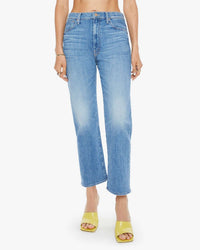 Wearing The Ditcher Zip Crop in Boogie Down by Mother, mid-blue stretch denim jeans, paired with yellow heeled sandals and a bare midriff, the look stands out against a plain white backdrop.