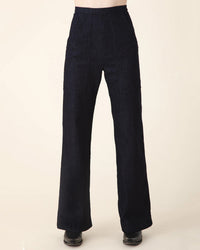 Person wearing Prairie Underground’s Yr Arrow Pant in Denim and black shoes, standing against a plain light background with only the lower body visible.