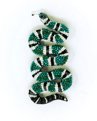The Green Banded Snake Brooch Pin by Trovelore is a hand-embroidered, snake-shaped accessory adorned with green, black, and white beads.