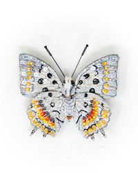 The Trovelore Jewel Nawab Butterfly Brooch Pin features intricate hand-embroidered silver, white, yellow, and orange sequins and beads on the wings with thin black antennae, displayed on a white background.