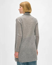 A person with short blonde hair, dressed in blue jeans and a White & Warren Cashmere Trapeze Cardigan in Grey Heather, stands facing away from the camera against a plain white background.