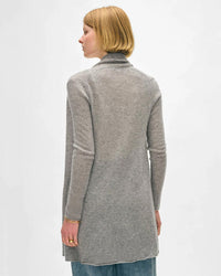 A person with short blonde hair, dressed in blue jeans and a White & Warren Cashmere Trapeze Cardigan in Grey Heather, stands facing away from the camera against a plain white background.