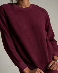 Wearing the Ziggy Inside Out Fleece L/S Shrunken Crew SS in Dark Burgundy by perfectwhitetee, a person stands against a plain background with their face partially out of frame. The sweatshirt features ribbed cuffs and collar.