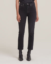 Wearing AGOLDE Riley Crop in Panoramic jeans with a straight leg cut, paired with black ankle boots and a black top, standing against a plain light background.
