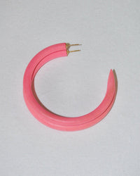 The B&L C Hoop in Large in Shrimp is a single pink hoop earring, handmade from sustainably sourced mango wood with a pointed end and a gold earring post, shown on a plain white surface.