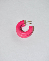 A single C Hoop in Mini in Knock Out Rose by B&L, a bright pink chunky earring handmade from sustainably sourced mango wood with gold posts, shaped like an incomplete circle and displayed on a light gray background.