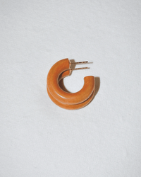 A single chunky, round C Hoop in Mini in Leather Weekender by B&L with a metal post rests on a light gray textured surface.