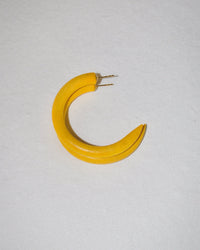 The B&L C Hoop in Small in Vegas Gold is a crescent-shaped, handmade earring reminiscent of a banana, featuring a unique two-prong detail and displayed on a plain, light background.