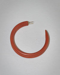 The B&L Large Hoop in Frank is a single red, crescent-shaped earring, hand-carved from sustainably sourced mango wood with gold posts, displayed on a plain white background.