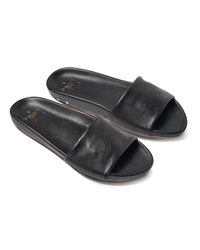 The Gallito in Black by beek. features black leather slides with wide straps, flat soles, and a molded footbed for comfort, shown on a white background.