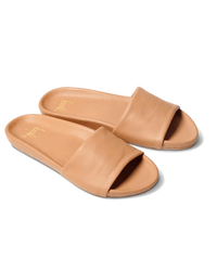 The beek.. Gallito in Honey slides feature tan leather, wide smooth straps, flat soles, and gentle arch support, shown on a white background.