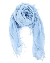 The Chan Luu Cashmere & Silk Scarf in Cashmere Blue features a gauzy texture and frayed edges, shown loosely rolled on a white background.