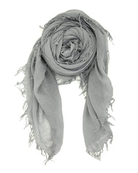 The Chan Luu Cashmere & Silk Scarf in Griffin, a light gray accessory with fringed trims, is rolled into a spiral with its loose ends draped elegantly on a white background.