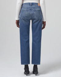 A person shown from the back against a plain light background wears Citizens of Humanity's Neve Low Slung Relaxed in Oasis jeans, a white ribbed long-sleeve top, and black heeled shoes.