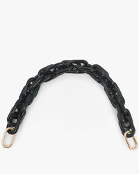 The Clare V. Shortie Strap in Black Acrylic features gold metal clasps at both ends and is shown curved on a plain white background, designed to complement Clare V. bags.