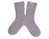 The Victorie Extra Soft Glittery Socks in Glycine Du Japon by Collegien are laid flat and crossed over each other, showcasing their subtle light purple sparkle on a white background.