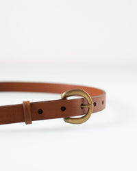 The Depalma Handsewn CL 3/4 inch Belt in Tobacco/Brass is shown partially coiled against a white background, highlighting its genuine leather, elegant brass buckle, and adjustment holes.