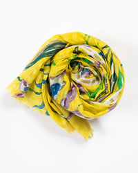 The Épice Meadow Orchids Scarf in Yellow, with a vibrant abstract floral design, is lightly rolled into a spiral and displayed on a white background.