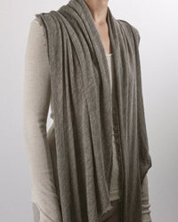 A person wears a light beige long-sleeve top paired with the Grisal Love Cashmere Scarf in Greige as a sleeveless, draped vest, standing against a plain light background. Their face is partially out of the frame.