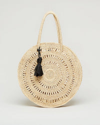 The Maison N.H Paris Cercle Medium in Natural is a round woven bag featuring two handles and a black tassel accent, shown against a plain, light background.
