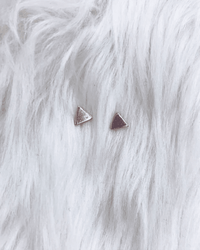 The Lucky Mini Triangle Posts in Silver by Nashelle are delicately placed on a soft, white, fluffy surface.